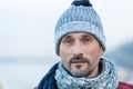 Portrait of white man in winter knitted hat and scarf. Close up of bearded guy in blue-white hat and scarf