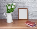 Portrait white picture frame mockup on vintage table with tulips jug vase and busines diary white brick wall background. Royalty Free Stock Photo