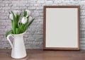 Portrait white picture frame mockup on vintage table with tulips jug vase grey white brick wall background. Royalty Free Stock Photo
