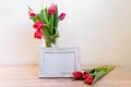 Portrait white picture frame mockup on wooden table. Modern vase with tulips.Scandinavian interior Royalty Free Stock Photo