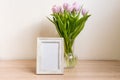 Portrait white picture frame mockup on wooden table. Modern vase with tulips.Scandinavian interior Royalty Free Stock Photo