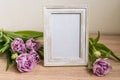 Portrait white picture frame mockup on wooden table. Modern vase with tulips.Scandinavian interior Royalty Free Stock Photo