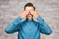 Portrait White young man dressed in blue shirt, closes eyes his hands. Man on brick wall background Royalty Free Stock Photo