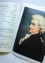 A portrait of Wolfgang Amadeus Mozart on the opened sheet music. Royalty Free Stock Photo