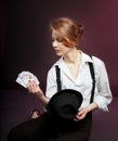 Portrait of woman, actress with playing cards in white shirt and stripped pants. Gambling, magic tricks.