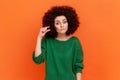 Portrait of woman with Afro hairstyle wearing green casual style sweater showing small size gesture