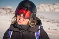 Portrait of a woman in the Alps. Smiling young woman in ski goggles and helmet stopped while skiing in ski resort