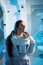 Portrait of a woman astronaut in a space suit, dreamy look up. Futuristic astronaut on Board the spacecraft.