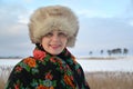 Portrait of the woman of average years in a fur cap and a colorful shawl against the winter lake Royalty Free Stock Photo