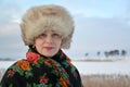 Portrait of the woman of average years in a fur cap and a colorul shawl against the winter lakef Royalty Free Stock Photo