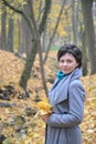 Portrait of the woman of average years with yellow maple leaves in hands