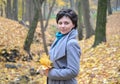 Portrait of the woman of average years with yellow maple leaves in hands