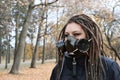 Portrait of a Woman in a black jacket with dreadlocks and a gas mask with spikes. Woman posing in autumn park Royalty Free Stock Photo