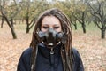 Portrait of a Woman in a black jacket with dreadlocks and a gas mask with spikes. Woman posing in autumn park and Royalty Free Stock Photo