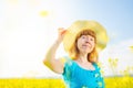 Portrait woman in blue dress and straw hat walk in yellow colza field