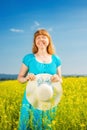 Portrait woman in blue dress and straw hat walk in yellow colza field