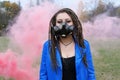 Portrait of a Woman in a blue jacket and dreadlocks in a gas mask with spikes. woman standing in smoke Royalty Free Stock Photo