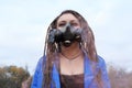 Portrait of a Woman in a blue jacket and dreadlocks in a gas mask with spikes. woman standing in smoke. Royalty Free Stock Photo