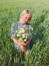 Portrait of woman with bouquet of camomiles and cornflowers in wheat field Royalty Free Stock Photo