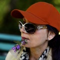 Portrait. A woman in a bright red baseball cap and black glasses.