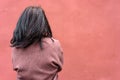 Portrait of a woman in a burgundy coat with long black hair view from the back