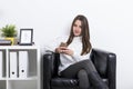 Portrait of a woman in casual clothes in an armchair with a mobi Royalty Free Stock Photo