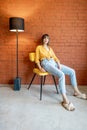 Portrait of a woman on chair on brick wall background Royalty Free Stock Photo