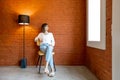 Portrait of a woman on chair on brick wall background Royalty Free Stock Photo
