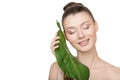 Portrait woman with clean skin smiling holds a green leaf in her hands. Skin care concept