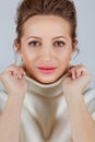 Portrait of a woman in close-up. A beautiful young woman holds the collar of a light sweater with both hands