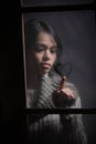 Portrait of woman drawing heart on wet window