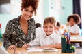 Portrait Of Woman Elementary School Teacher Giving Male Pupil Wearing Uniform One To One Support Royalty Free Stock Photo