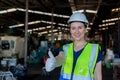 Portrait of woman engineer wear white helmet thumbs up in uniform standing at industrial workshop. Copy space Royalty Free Stock Photo