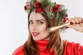 Portrait of a woman with a fir wreath with cones on her head, holds in her hand a nozzle for a cosmetic procedure.