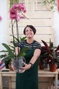 Portrait of woman florist with orchid phalaenopsis in apron and tool in flower shop