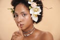 Portrait of woman with flowers in hair doing silent gesture with finger