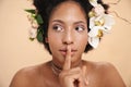 Portrait of woman with flowers in hair doing silent gesture with finger