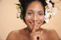 Portrait of woman with flowers in hair doing silent gesture with finger