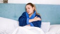 Portrait of young woman with flu lying under blanket in bed Royalty Free Stock Photo