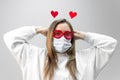 Portrait of woman in funny glasses and medical protective wearing mask holding in hands red hearts. concept of valentines day Royalty Free Stock Photo