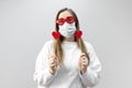 Portrait of woman in funny glasses and medical protective wearing mask holding in hands red hearts. concept of valentines day Royalty Free Stock Photo