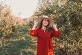 Portrait of a woman in the garden. A young and beautiful woman in a red dress holding her hands to her hat and smiling sweetly Royalty Free Stock Photo