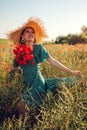 Portrait of woman gathered bouquet of poppies flowers walking in summer field. Stylish girl in straw hat admires view