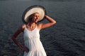 Portrait of a woman in a hat. A beautiful happy young blonde in a white summer dress and a straw hat on her head poses Royalty Free Stock Photo