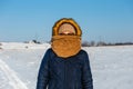 Portrait of a woman hidden behind her scarf. Sunny winter day