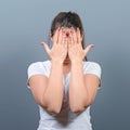 Portrait of woman hiding her face with both hands against gray background Royalty Free Stock Photo