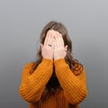 Portrait of woman hiding her face with both hands against gray background Royalty Free Stock Photo