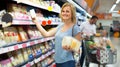 Portrait of woman holding assortment of cheese in grocery shop