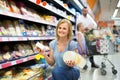 Portrait of woman holding assortment of cheese in grocery shop