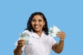 Portrait of woman holding Brazilian 100 reais banknotes in hands, afro brazilian, confident